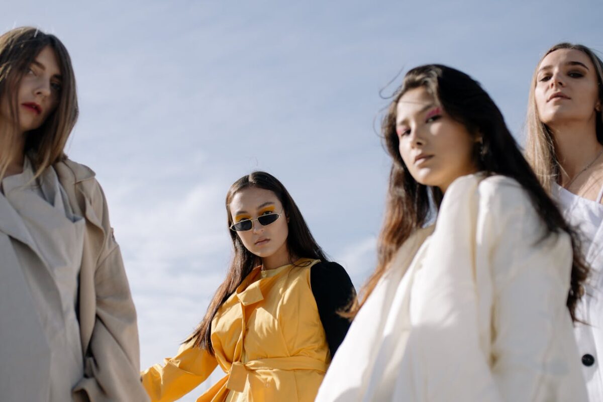 Service Fashionable women posing confidently in chic outfits under the clear sky.