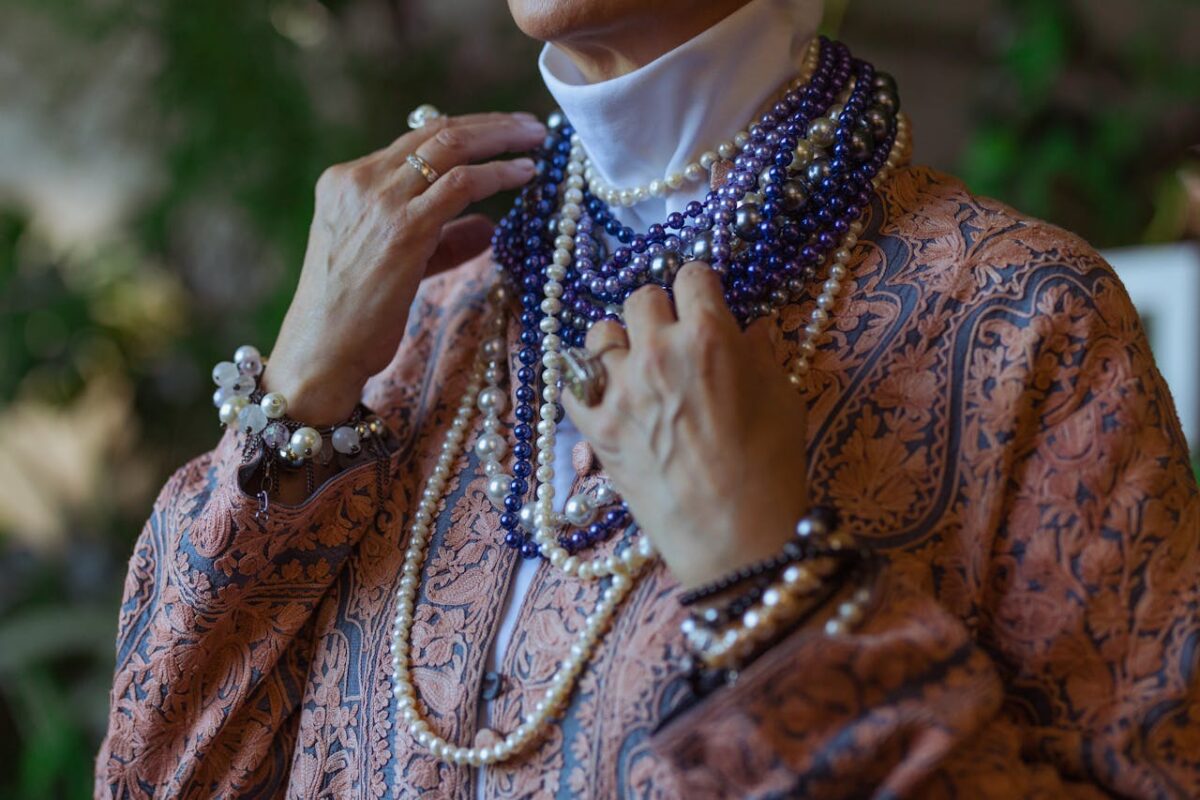 Close-up of a senior woman wearing multiple strands of pearls and beaded jewelry, showcasing boho style.