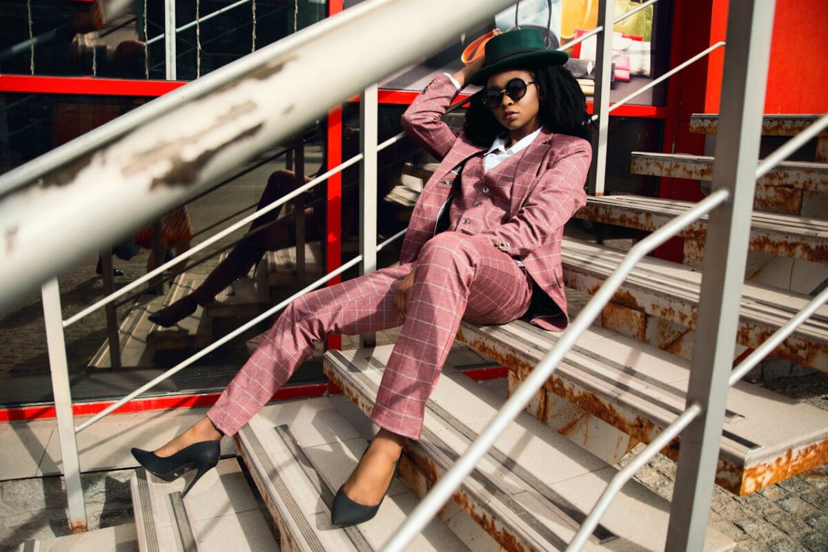Service Fashionable woman in pink plaid suit and hat posing on an urban staircase.